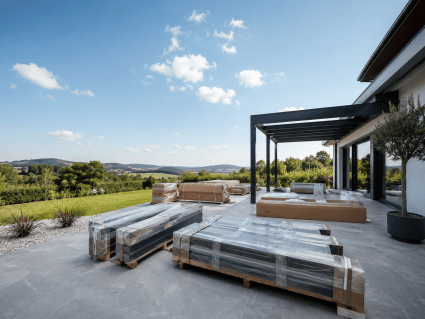 AirCube Lamellendach-Pergola Lieferung und Vorbereitung auf moderner Terrasse mit verpackten Bauteilen